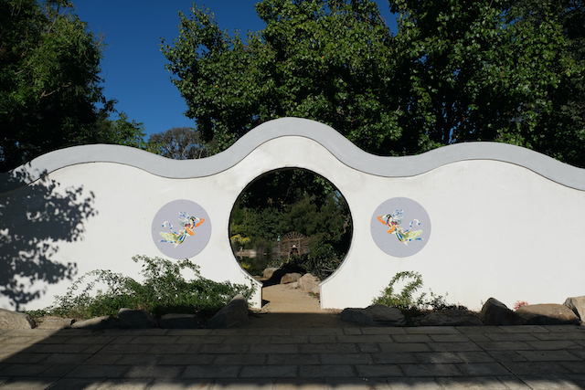 White wall with circular gate to garden room